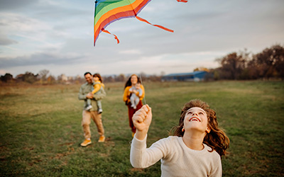 Kind spielt mit einem Drachen im Kreis der Familie.