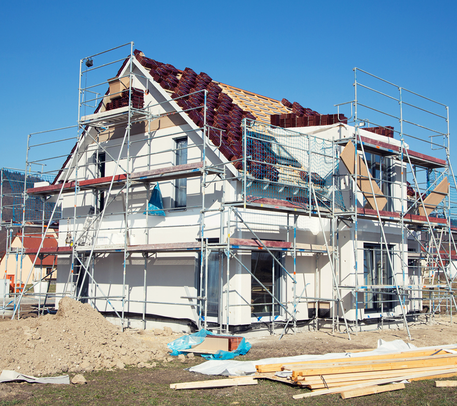 Baustelle mit eingerüstetem im Bau befindlichem Einfamilienhaus.