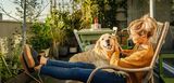 Frau mit Hund auf großem Balkon.