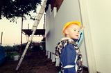 Ein Kind mit Helm auf der Baustelle. Das Baukindergeld soll Familien beim Erwerb von Wohneigentum unterstützen. 