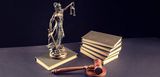 Symbole für Rechtsprechung und Gerechtigkeit: Justitia, Göttin von Recht und Gesetz, ein Richterhammer aus Holz und ein Stapel von (Gesetz-) Büchern. Vermieter können Mietnomaden verklagen.  