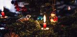 Weihnachtsbaum mit Kerze und reichlich Baumschmuck. Sciher durch Advents- und Weihnachtseit mit unseren 7 Tipps für den richtigen Umgang mit Kerzen