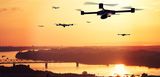 Drohnen nähern sich unter dramatischem orangen Himmel, die Sonne geht unter. Man ist erinnert an Apokalypse Now, Wagner und Hubschrauber. Die Drohne sind zwar unbemannt, aber das Szenario wirkt bedrohlich. 