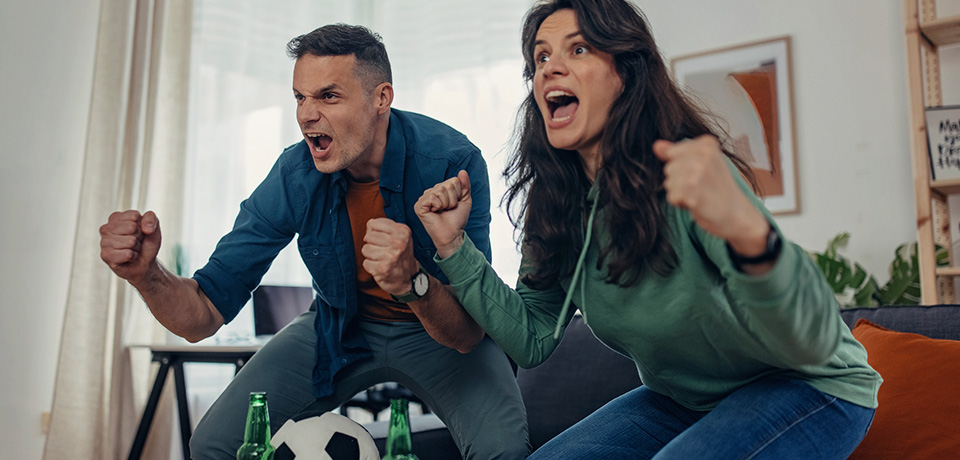 Jubelnde Fußballfans daheim. Mit einer guten und günstigen Hausratversicherung wie unserer HomeCare Top kann man das Leben genießen.