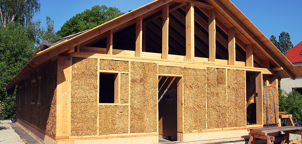Ein im Bau befindliches Holzhaus, in das Strohballenwärmedämmung eingebaut wird. 