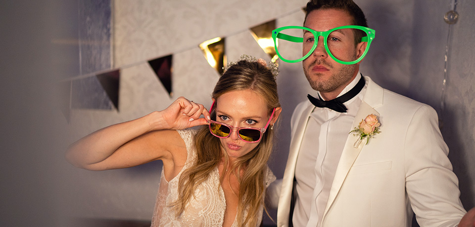 Hochzeitspaar mit großer Brille für den richtigen Durchblick: Das ändert sich bei den Versicherungen für Ehepaare und Familien. 