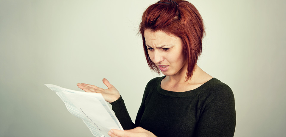Frau liest verärgert den Brief ihres Vermieters mit der Ankündigung einer Mieterhöhung. 