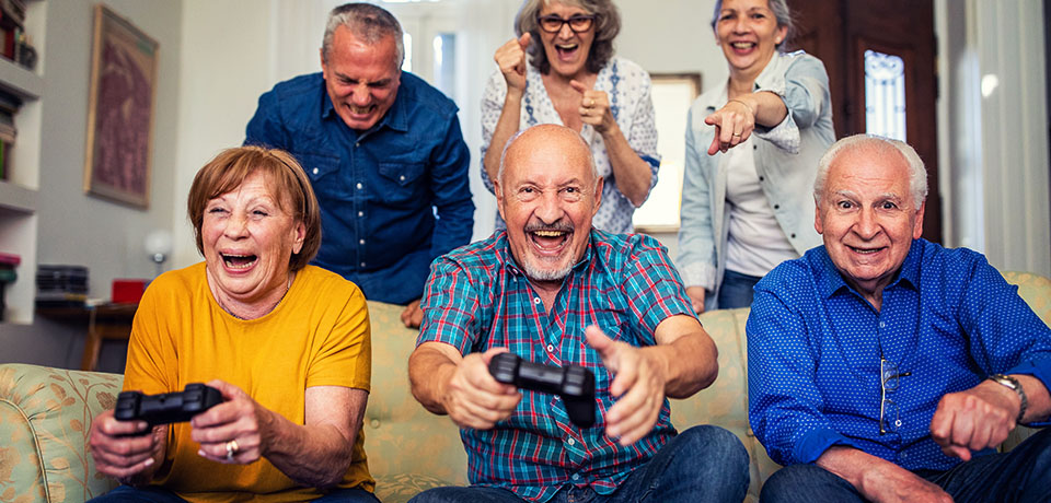 Senioren mit Spielkonsolen haben viel Spaß und feiern miteinander.  Damit Senioren lange sin ihren Wohnungen wohnen und sicher bleiben, haben wir ein paar Tipps zusammengestellt.